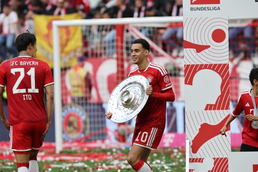 Bayern Munich's German midfielder #10 Jamal Musiala celebrates with the Bundesliga trophy near Bayern Munich's Japanese defender #21 Hiroki Ito after the German first division Bundesliga football match between FC Bayern Munich and FC Cologne in Munich, southern Germany, on May 16, 2026. Alexandra BEIER / AFP