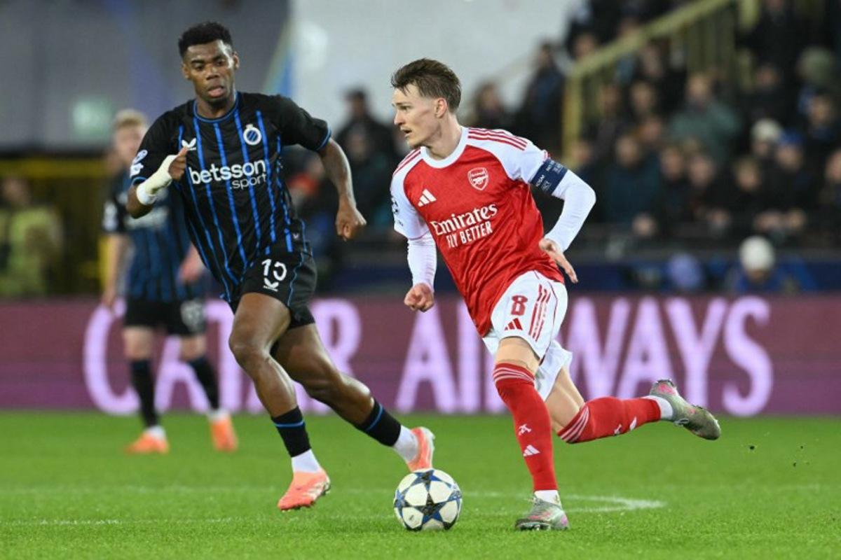 Arsenal's Norwegian midfielder #08 Martin Odegaard (R) runs with the ball during the UEFA Champions League, league phase - matchday 6, football match between Club Brugge and Arsenal at the Jan Breydel stadium in Bruges on December 10, 2025. NICOLAS TUCAT / AFP