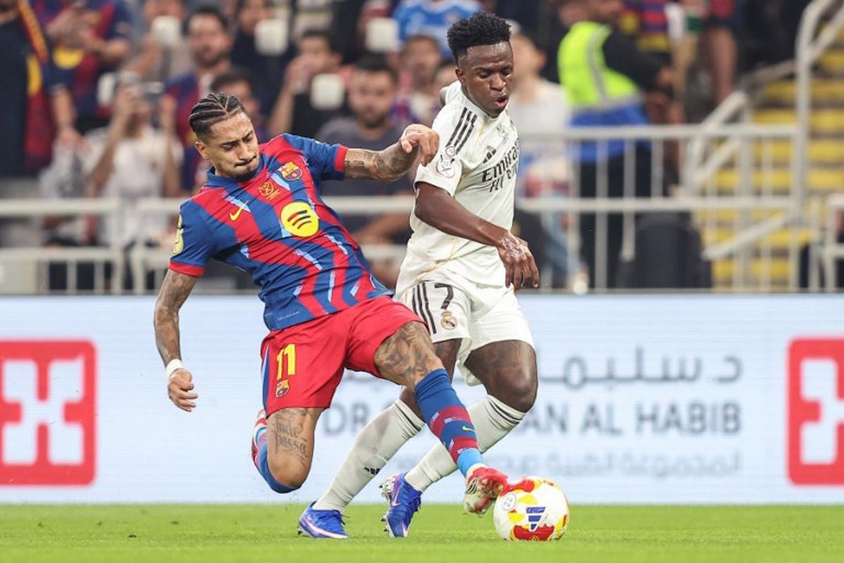 Barcelona's Brazilian forward #11 Raphinha (L) and Real Madrid's Brazilian forward #07 Vinicius Junior fight for the ball during the Spanish Super Cup final football match between FC Barcelona and Real Madrid at the King Abdullah Stadium in Jeddah on January 11, 2026. Haitham AL-SHUKAIRI / AFP
