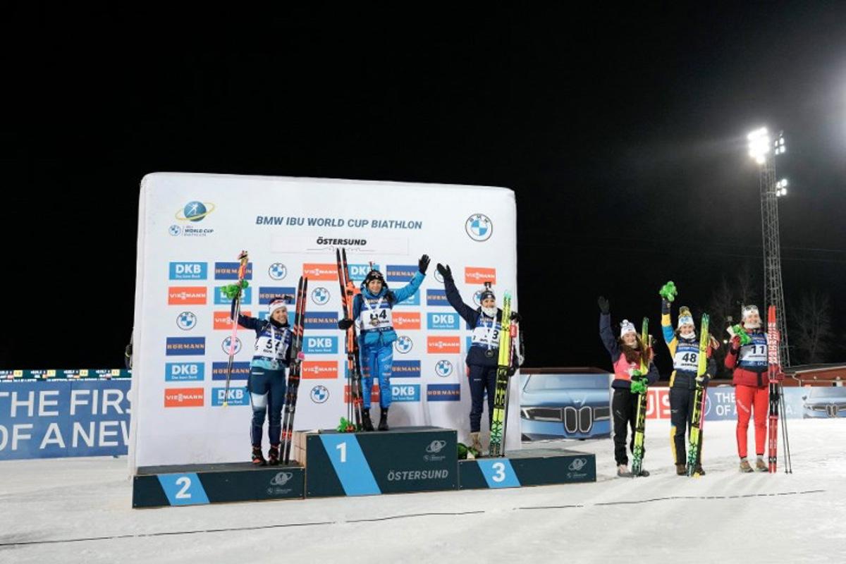 (L-R) Second placed Finland's Sonja Leinamo, first placed Italy's Dorothea Wierer and third placed France's Camille Bened celebrate on the podium after winning the women's 15km individual event of the IBU Biathlon World Cup in Oestersund, Sweden on December 2, 2025, followed next to the podium by fourth placed France's Lou Jeanmonnot, fifth placed Sweden's Hanna Oeberg and sixth placed Belgium's Maya Cloetens. Bjorn LARSSON ROSVALL / TT NEWS AGENCY / AFP