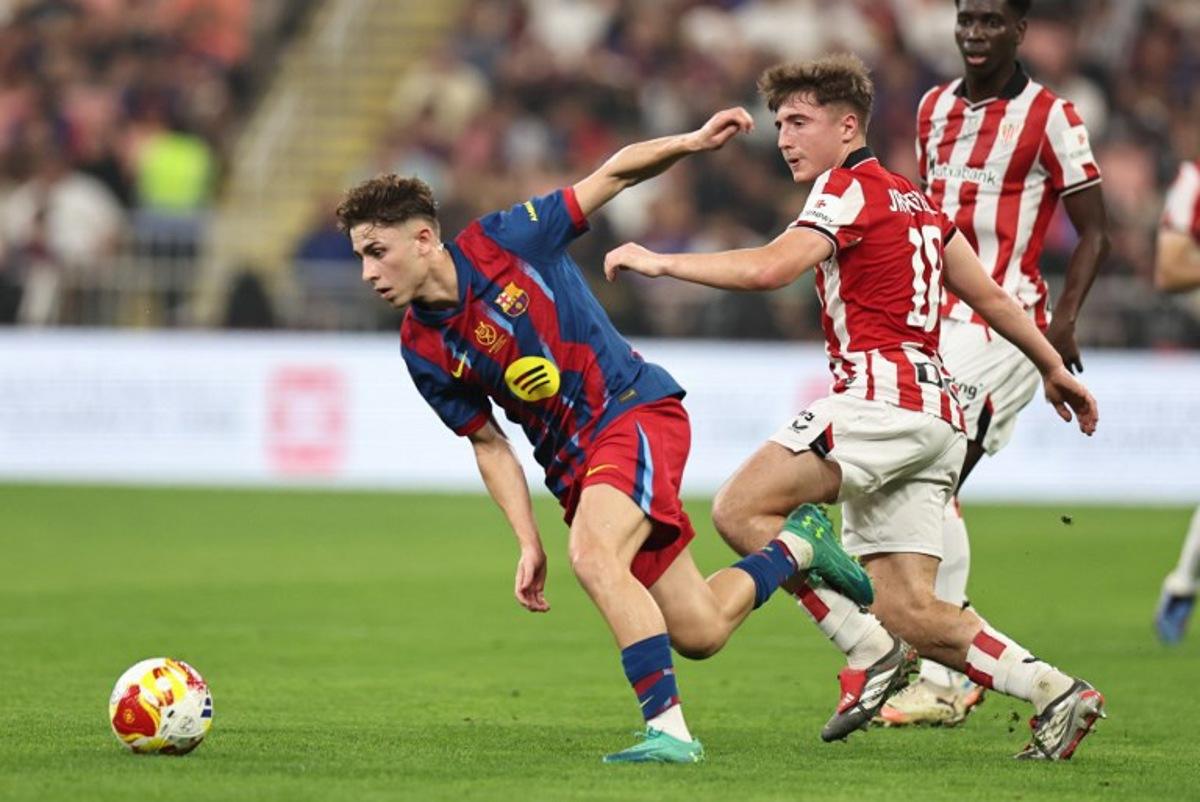 Barcelona's Spanish midfielder #16 Fermin Lopez runs for the ball with Athletic Bilbao's Spanish midfielder #18 Mikel Jauregizar Alboniga during the Spanish Supercup semi-final football match between FC Barcelona and Athletic Bilbao at King Abdullah Sports City in Jeddah on January 7, 2026. Fadel SENNA / AFP
