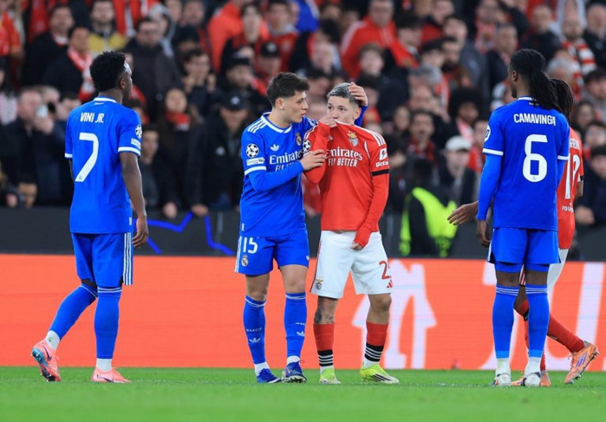 SL Benfica's Argentine forward #25 Gianluca Prestianni hides his mouth while arguing with Real Madrid's Brazilian forward #07 Vinicius Junior who complained about alleged racists insults during the UEFA Champions League knockout round play-off first leg football match between SL Benfica and Real Madrid CF at Estadio da Luz in Lisbon on February 17, 2026. PATRICIA DE MELO MOREIRA / AFP