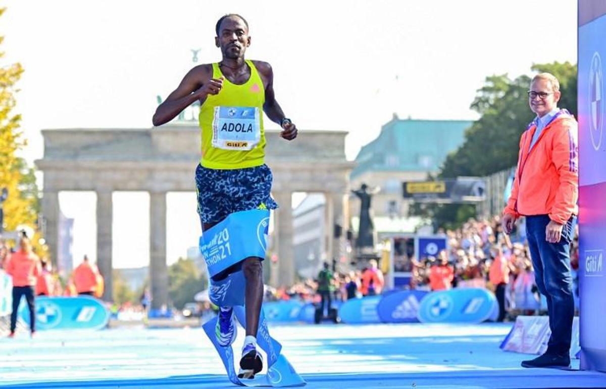Ethiopia's GuyeAdola runs to win the Berlin Marathon on September 26, 2021 in front of Brandenburg Gate in Berlin, as Berlin's Mayor Michael Mueller (R) looks on. Tobias SCHWARZ / AFP