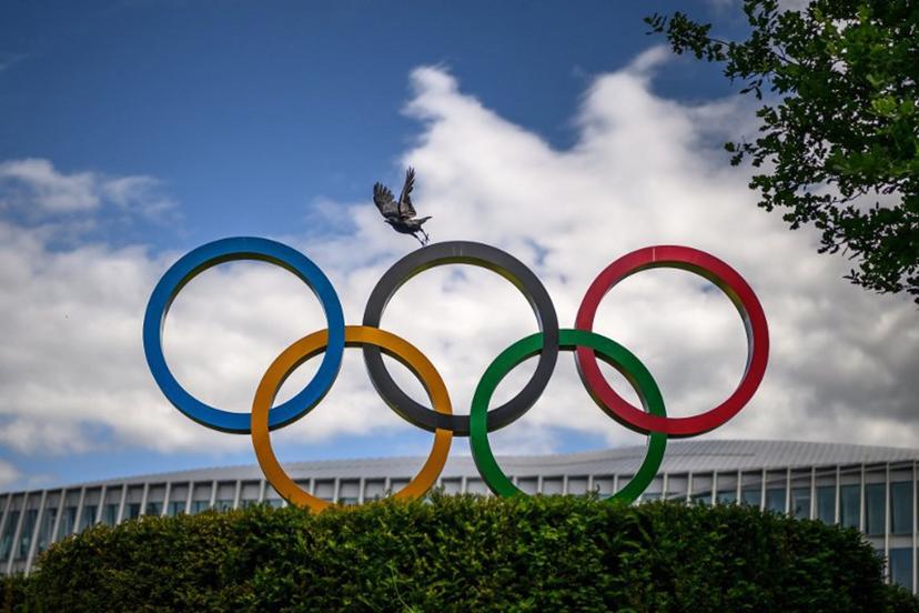 A crow flies above the Olympics Rings displayed at the headquarters of the International Olympic Committee (IOC) in Lausanne on May 13, 2026. Fabrice COFFRINI / AFP