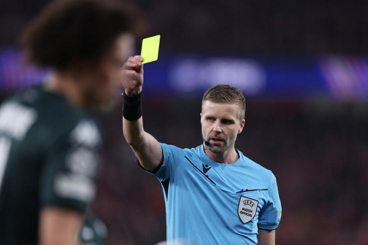 Referee Glenn Nyberg shows a yellow card to Monaco's French midfielder #11 Maghnes Akliouche during the UEFA Champions League knockout phase play-off second leg football match between SL Benfica and AS Monaco at Luz stadium in Lisbon on February 18, 2025. FILIPE AMORIM / AFP