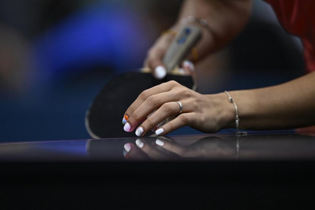 A detailed view of India's Manika Batra's nails painted with the Indian flag and Olympic Rings as she prepares to serve the ball during her women's table tennis singles match in the team quarter-finals between India and Germany at the Paris 2024 Olympic Games at the South Paris Arena in Paris on August 7, 2024. WANG Zhao / AFP