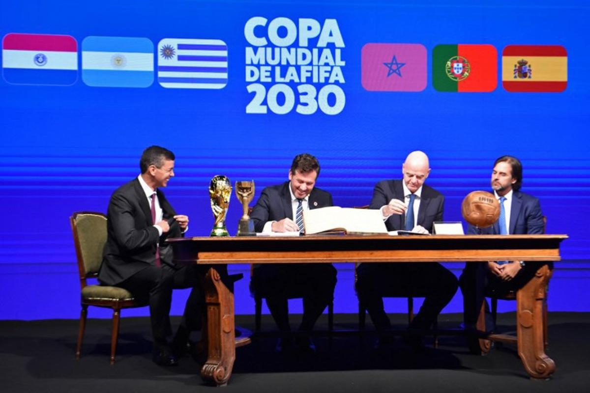 Conmebol's President Alejandro Dominguez (L-2) and FIFA President Gianni Infantino (R-2), accompanied by Paraguay's President Santiago Peña (L) and Uruguay's President Luis Lacalle(R), sign a book of minutes of the 2030 World Cup during Conmebol's 78th Ordinary Congress in Luque, Paraguay on April 11, 2024. NORBERTO DUARTE / AFP
