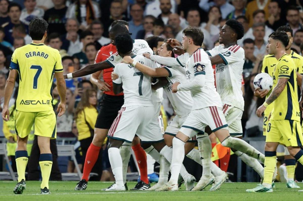 Real Madrid's Brazilian forward #07 Vinicius Junior (C) is restrained by teammates as he argues with referee Isidro Escuderos after receiving a red card during the Spanish league football match between Real Madrid CF and Villarreal CF at the Santiago Bernabeu Stadium in Madrid on October 10, 2026. Oscar DEL POZO / AFP