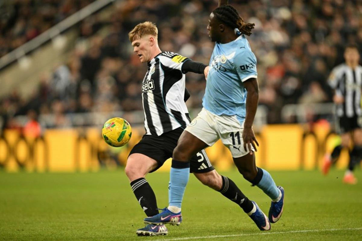 Newcastle United's English midfielder #20 Lewis Hall (L) vies with Manchester City's Belgian midfielder #11 Jeremy Doku (R) during the English League Cup semi-final first leg football match between Newcastle United and Manchester City at St James' Park in Newcastle-upon-Tyne, north east England on January 13, 2026. Oli SCARFF / AFP
