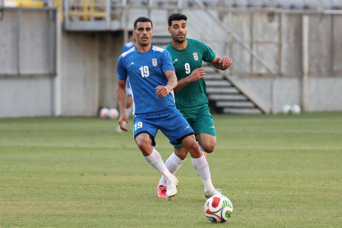 Iran's forward #9 Mehdi Taremi (green) and Iran's defender #19 Milad Mohammadi (blue) practice during a training session as part of the team's preparation for the upcoming football World Cup at the Iranian national team's base camp in Antalya on May 26, 2026. Oner SAN / AFP