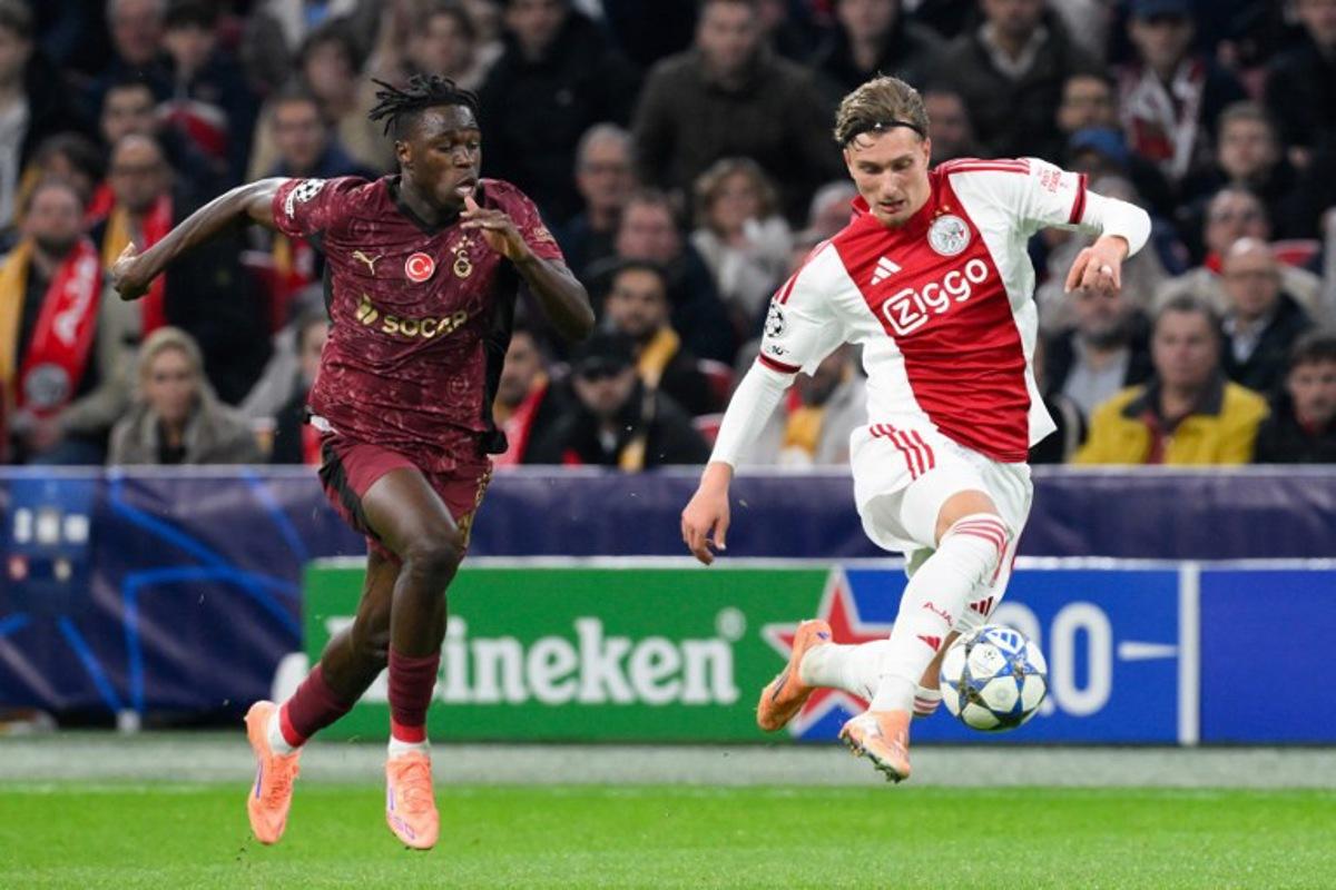 Ajax's Belgian forward #11 Mika Godts (R) fights for the ball with Galatasaray's Ivorian defender #90 Wilfried Singo (L) during the UEFA Champions League, league phase day 4, football match between Ajax and Galatasaray at the Johan Cruijff ArenA in Amsterdam on November 5, 2025. JOHN THYS / AFP