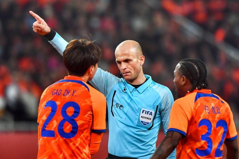 Shandong Taishan's Gao Zhunyi (L) receives a warning from referee Adham Mohammad Makhadmeh during the AFC Champions League quarterfinal match between Japan's Yokohama F Marinos and China's Shandong Taishan in Jinan, in China's eastern Shandong province on March 6, 2024. STR / AFP