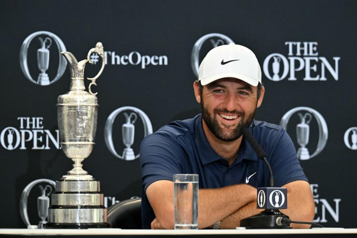 US golfer Scottie Scheffler with the Claret Jug, the trophy for the Champion golfer of the year beside him, holds a press conference after his victory in the 153rd Open Championship at Royal Portrush golf club in Northern Ireland on July 20, 2025. Scottie Scheffler romped to a magnificent four-shot victory to seal his first British Open title at Royal Portrush on Sunday, notching his fourth major success. The world number one eased to a three-under par final round of 68, finishing on 17-under for the tournament after shooting in the 60s on all four days. ANDY BUCHANAN / AFP