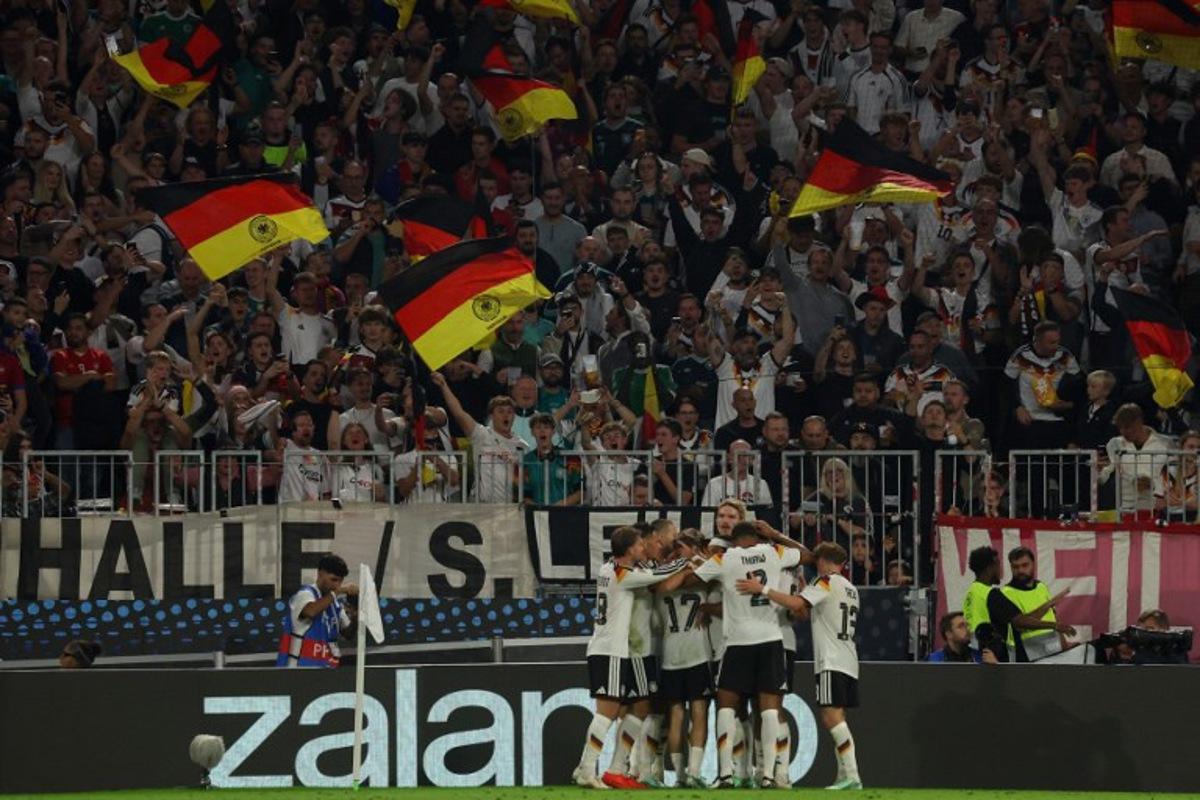 Germany's midfielder #08 Tom Bischof (hidden) celebrates scoring the opening goal with his teammates during the UEFA Nations League Group A2 between Germany and Serbia at the Allianz Arena in Munich, southern Germany on October 1, 2026. Karl-Josef HILDENBRAND / AFP