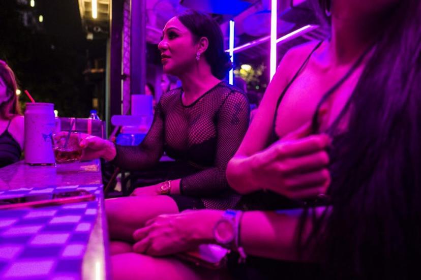 Emily (C), a sex worker, sits with her colleagues as they wait for clients in the back of a bar in Pattaya on July 2, 2026. Scantily dressed and wearing stiletto heels, hundreds of girls, some apparently very young, form a seedy guard of honour under the lights of Soi 6, a street in one of Pattaya's red-light districts. ANTHONY WALLACE / AFP
