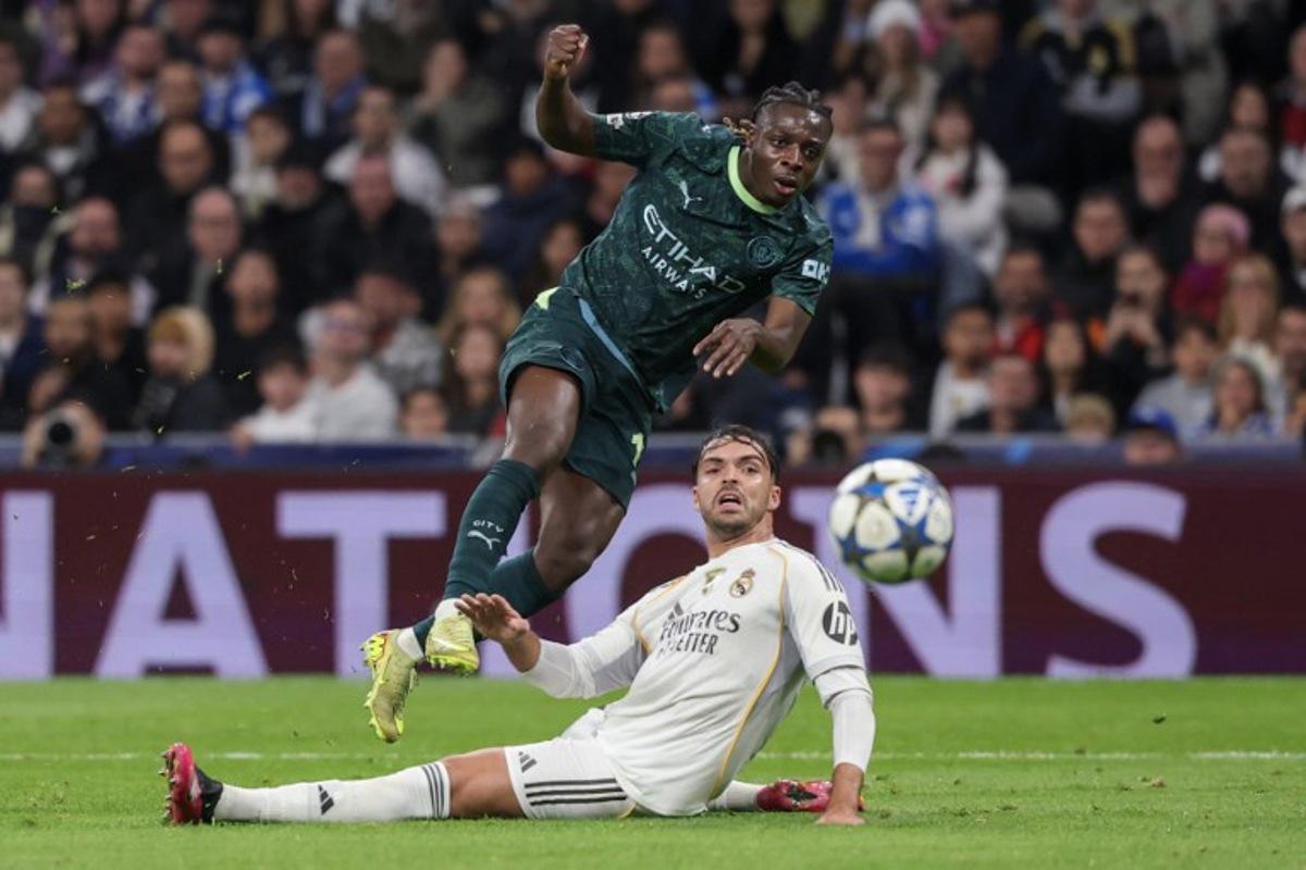 Manchester City's Belgian forward #11 Jeremy Doku shoots past Real Madrid's Spanish defender #35 Raul Asencio but fails to score during the UEFA Champions League league phase day 6 football match between Real Madrid CF and Manchester City at Santiago Bernabeu Stadium in Madrid on December 10, 2025. Pierre-Philippe MARCOU / AFP